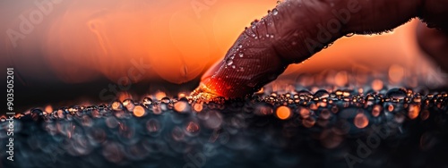  A hand in close-up, touching a substance on a surface, with water droplets forming thereon photo