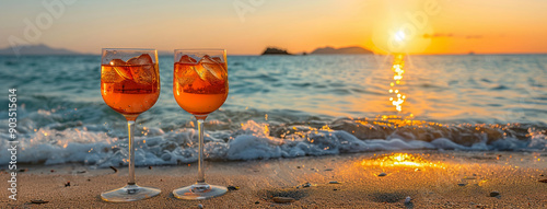 Two Aperol cocktails on the beach by the sea in the rays of the setting sun against a backdrop of sea waves and sand. With room for a text. Hello summer. photo