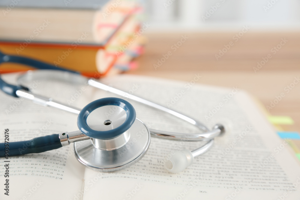 One new medical stethoscope and books on wooden table, closeup One new medical stethoscope and books on wooden table, closeup