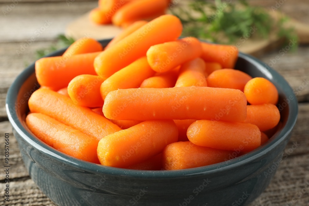 Baby carrots in bowl on wooden table, closeup Baby carrots in bowl on wooden table, closeup