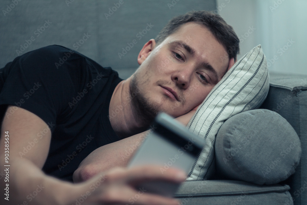 A man is procrastinating: sitting with a phone in his hands, relaxed position, concentrated gaze on the screen, expression A man is procrastinating: sitting with a phone in his hands, relaxed position, concentrated gaze on the screen, expression