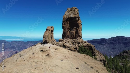 Aerial view of people hiking in Gran Canaria at Roque Nublo mountain geologic rock formation. Drone view of Teide and Tejeda in the background photo