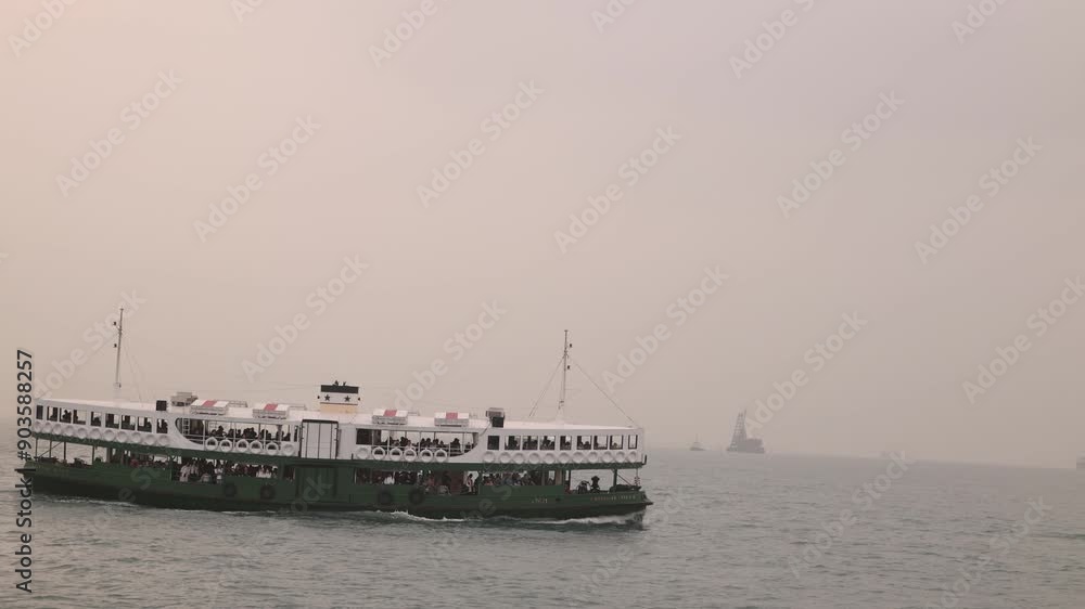 A ferry sails in Hong Kong harbor on a hazy day with distant boats and faint skyline A ferry sails in Hong Kong harbor on a hazy day with distant boats and faint skyline