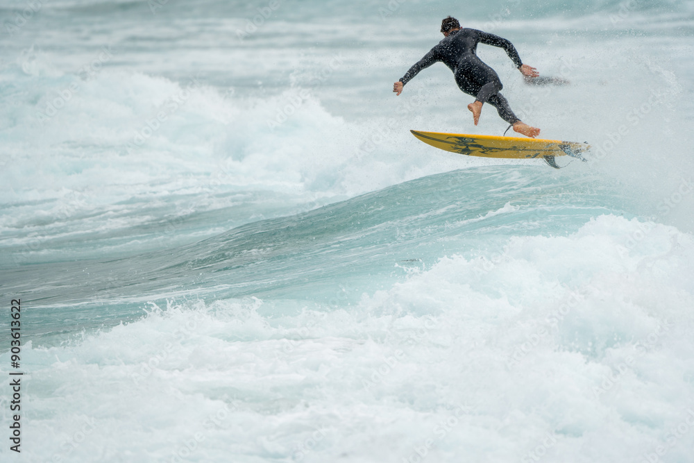 surfer on the wavesCaucasian male surfer Australian from behind in air after catching a wave, surfer on the wavesCaucasian male surfer Australian from behind in air after catching a wave,