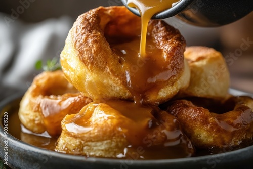 Delicious Golden Yorkshire Puddings with Rich Savory Gravy Being Poured Over for a Mouthwatering Culinary Delight.