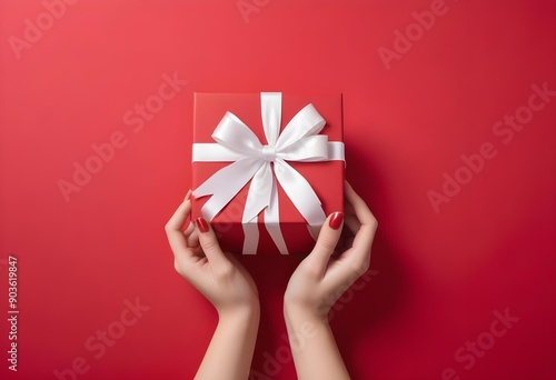 Red gift box with a white ribbon bow on a bright red background