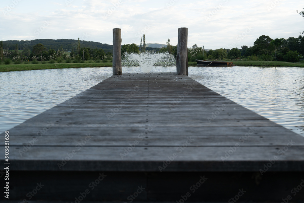 Fototapeta premium Rustic wooden pier dock on lake water fountain 