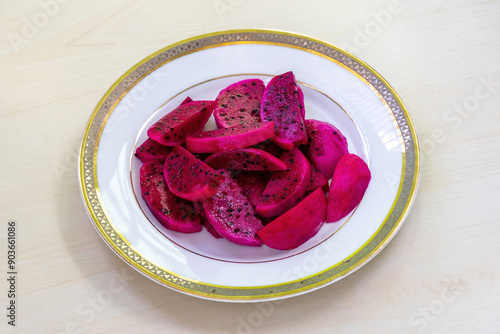 Dragon fruit cut pieces on a white plate on wooden background. photo