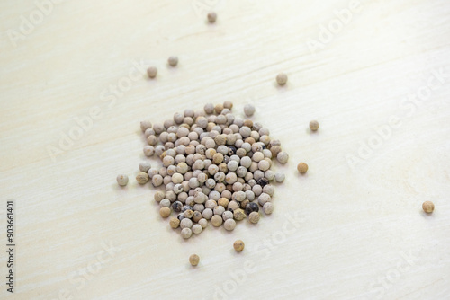 Dry white peppercorn (Piper nigrum) spice seeds on wooden background. photo