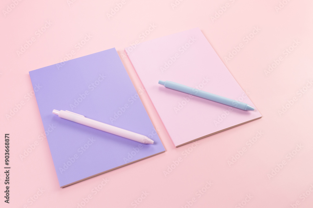 Top view of pink and purple notebooks on pink background. Pink and blue pens, school, office wallpaper. Flat lay, copy space. Top view of pink and purple notebooks on pink background. Pink and blue pens, school, office wallpaper. Flat lay, copy space.