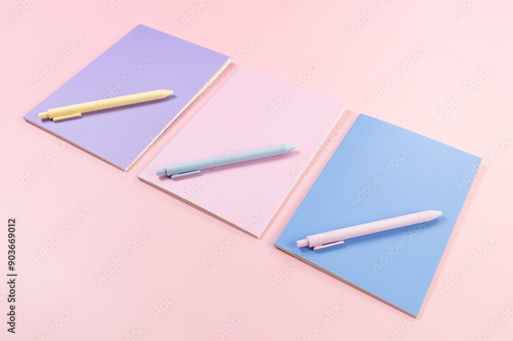 Top view of pink, purple and blue notebooks on pink background. Pink, yellow and blue pens, school, office wallpaper. Flat lay, copy space. Top view of pink, purple and blue notebooks on pink background. Pink, yellow and blue pens, school, office wallpaper. Flat lay, copy space.