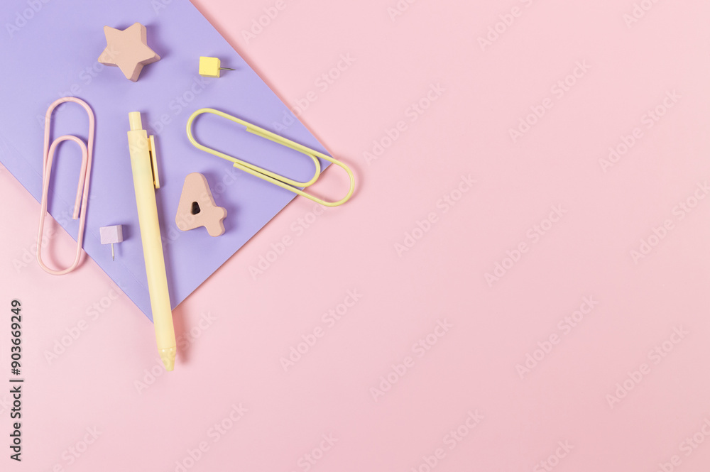 Top view of purple notebook on pink background. Paperclips, pen, number, shape and pins. School, office wallpaper. Flat lay, copy space. Top view of purple notebook on pink background. Paperclips, pen, number, shape and pins. School, office wallpaper. Flat lay, copy space.
