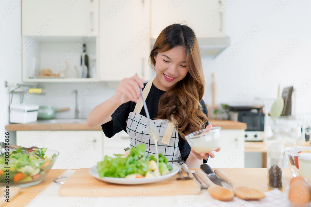 Young asian woman use spoon to adding mayonnaise into salad on plate while preparing fresh vegetables salad in bowl and cooking healthy breakfast food in modern kitchen with healthy lifestyle at home Young asian woman use spoon to adding mayonnaise into salad on plate while preparing fresh vegetables salad in bowl and cooking healthy breakfast food in modern kitchen with healthy lifestyle at home