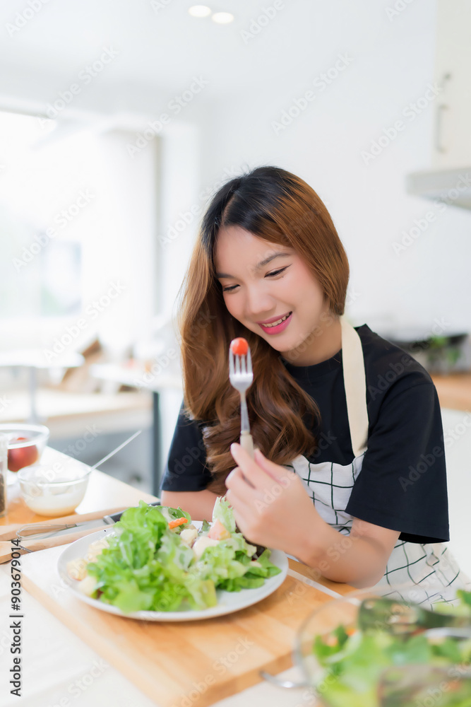Young asian woman eating tomatoes in vegetables salad with happiness after mixing fresh vegetables salad with dressing and cooking healthy breakfast food in kitchen with healthy lifestyle at home Young asian woman eating tomatoes in vegetables salad with happiness after mixing fresh vegetables salad with dressing and cooking healthy breakfast food in kitchen with healthy lifestyle at home