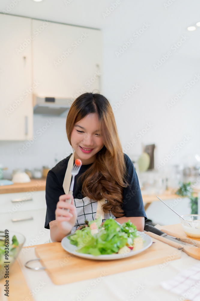 Young asian woman eating tomatoes in vegetables salad with happiness after mixing fresh vegetables salad with dressing and cooking healthy breakfast food in kitchen with healthy lifestyle at home Young asian woman eating tomatoes in vegetables salad with happiness after mixing fresh vegetables salad with dressing and cooking healthy breakfast food in kitchen with healthy lifestyle at home