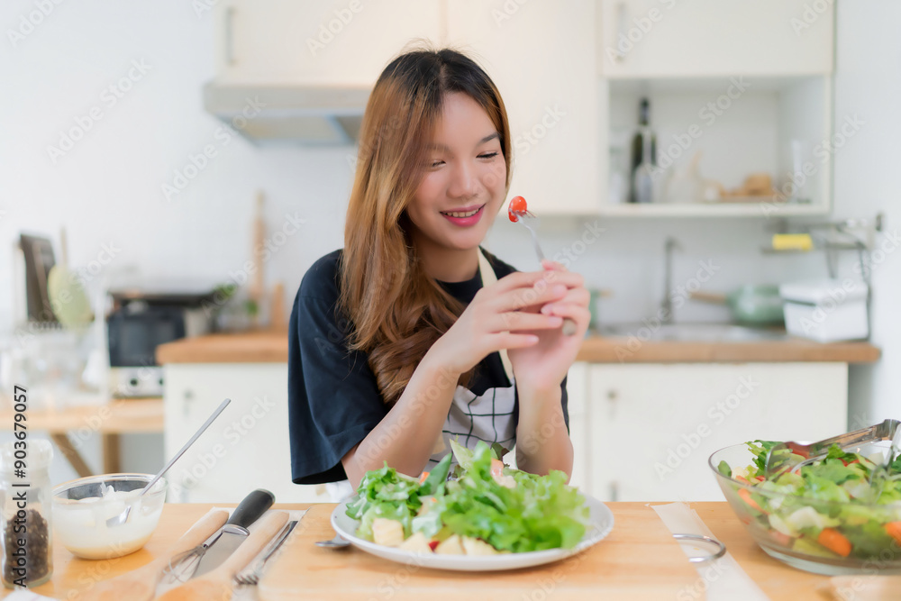 Young asian woman eating tomatoes in vegetables salad with happiness after mixing fresh vegetables salad with dressing and cooking healthy breakfast food in kitchen with healthy lifestyle at home Young asian woman eating tomatoes in vegetables salad with happiness after mixing fresh vegetables salad with dressing and cooking healthy breakfast food in kitchen with healthy lifestyle at home
