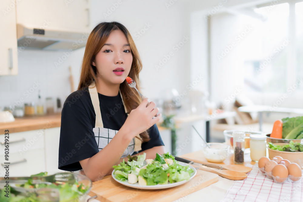 Young asian woman enjoying with eating tomatoes in vegetables salad after mixing fresh vegetables salad with mayonnaise and cooking healthy breakfast food in kitchen with healthy lifestyle at home Young asian woman enjoying with eating tomatoes in vegetables salad after mixing fresh vegetables salad with mayonnaise and cooking healthy breakfast food in kitchen with healthy lifestyle at home