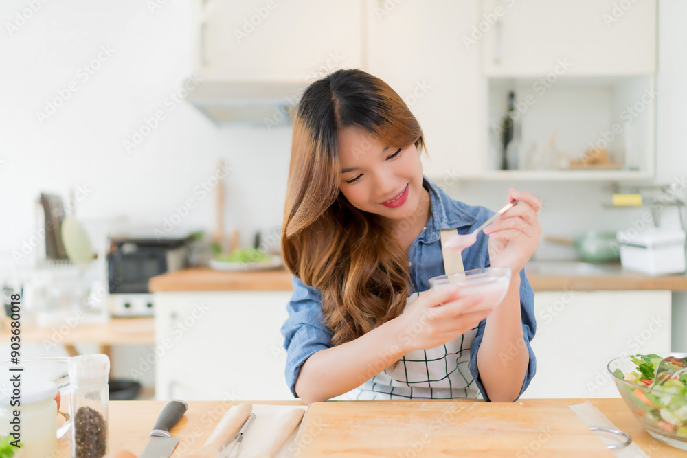 Young asian woman having breakfast to eating delicious yogurt with teaspoon after preparing fresh vegetables salad and making healthy breakfast food in modern kitchen with healthy lifestyle at home Young asian woman having breakfast to eating delicious yogurt with teaspoon after preparing fresh vegetables salad and making healthy breakfast food in modern kitchen with healthy lifestyle at home