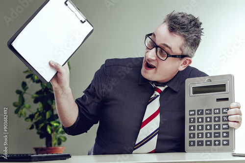 Accountant celebrating with calculator and clipboard at workplac photo