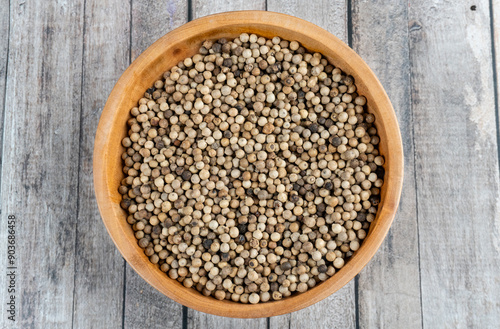 top view of a wooden bowl of coriander seeds on wooden table