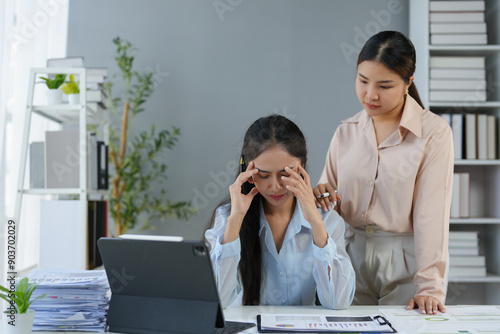 Fotografie Asian businesswomen and office workers who are stressed out, feeling tired, sick, crying, and demotivated, have co-workers standing beside them to help them encourage them