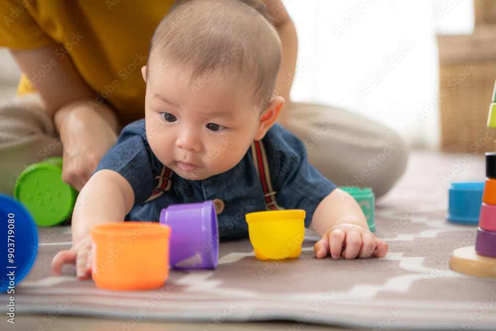 A tiny child cheerfully plays with toys on the floor of the living room with mom A tiny child cheerfully plays with toys on the floor of the living room with mom