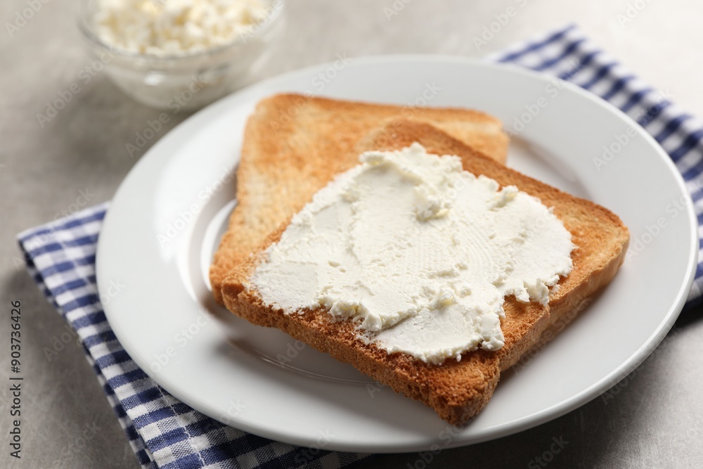 Delicious toasted bread slices with cream cheese on grey table Delicious toasted bread slices with cream cheese on grey table