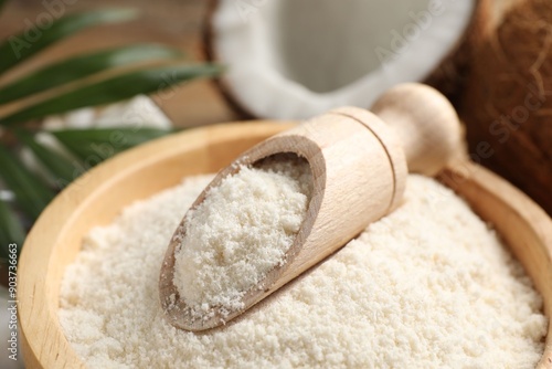 Coconut flour in bowl and scoop on table, closeup