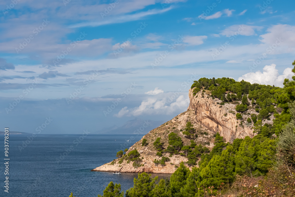 Fototapeta premium Breathtaking coastal vista featuring a rugged cliff rising dramatically from crystalline blue sea of Adriatic sea along Makarska Riviera coastline Split-Dalmatia, Croatia, Europe. Travel destination