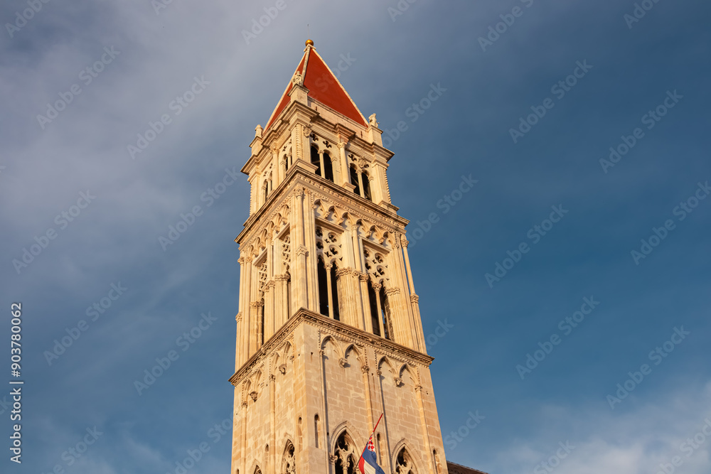 Fototapeta premium Imposing bell tower of Cathedral of St. Lawrence (San Lorenzo) against a dramatic sky in historic old town Trogir, Split-Dalmatia, Croatia, Europe. Tourist travel destination at Adriatic Sea.