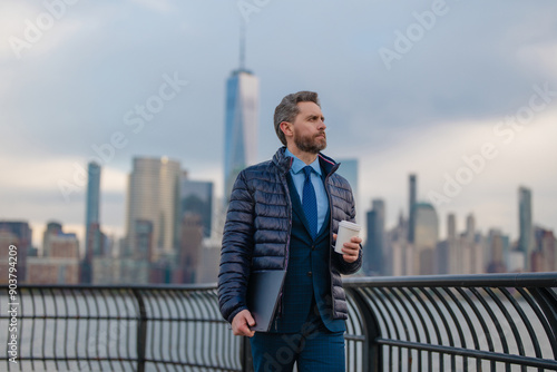 Business man in warm jacket drink coffee in NYC. Businessman in winter New York, Manhattan. Handsome business man outside in winter. Mature man in jacket walking on street drink take away coffee.