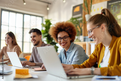 Group of young professionals collaborating on laptops in modern office
