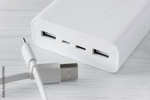 Powerbank for charging mobile devices with cable on white table
