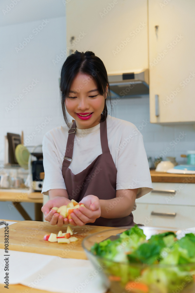 Asian women picking slices apple on cutting board into her hands to preparing fresh fruits of ingredients for cooking breakfast meal and salad while making healthy food lifestyle in kitchen at home Asian women picking slices apple on cutting board into her hands to preparing fresh fruits of ingredients for cooking breakfast meal and salad while making healthy food lifestyle in kitchen at home