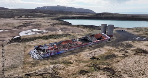 Video footage explores an abandoned Iceland farm, with a collapsed roof, scattered debris, and surrounding grasslands, highlighting nature's transformative power. photo