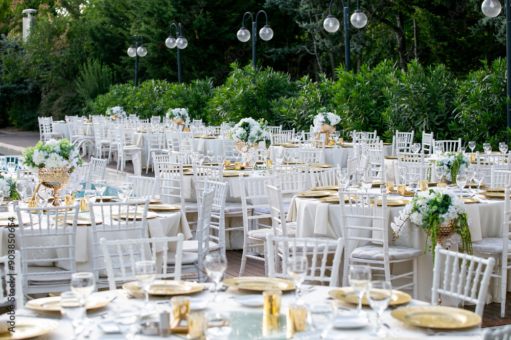 Elegant outdoor wedding reception with white chairs and floral centerpieces