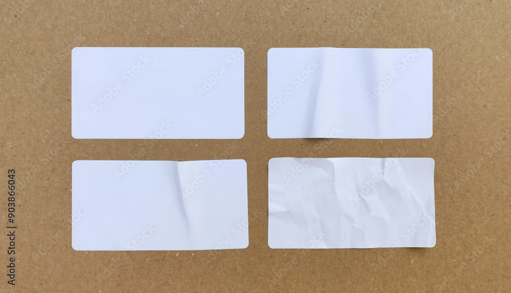 Blank white paper sticker label set isolated on cardboard background Blank white paper sticker label set isolated on cardboard background