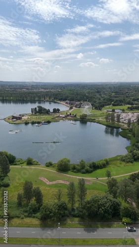 Wide aerial dolly parallax of Willen Lake, Milton Keynes. Features Willen Lake ferris wheel, with South/East Milton Keynes in the background