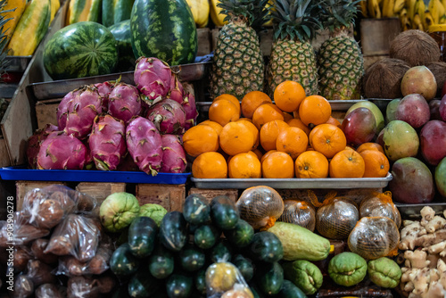 tropical fruits in a traditional market, including coconut, pitahaya, pineapple, mango, and ginger