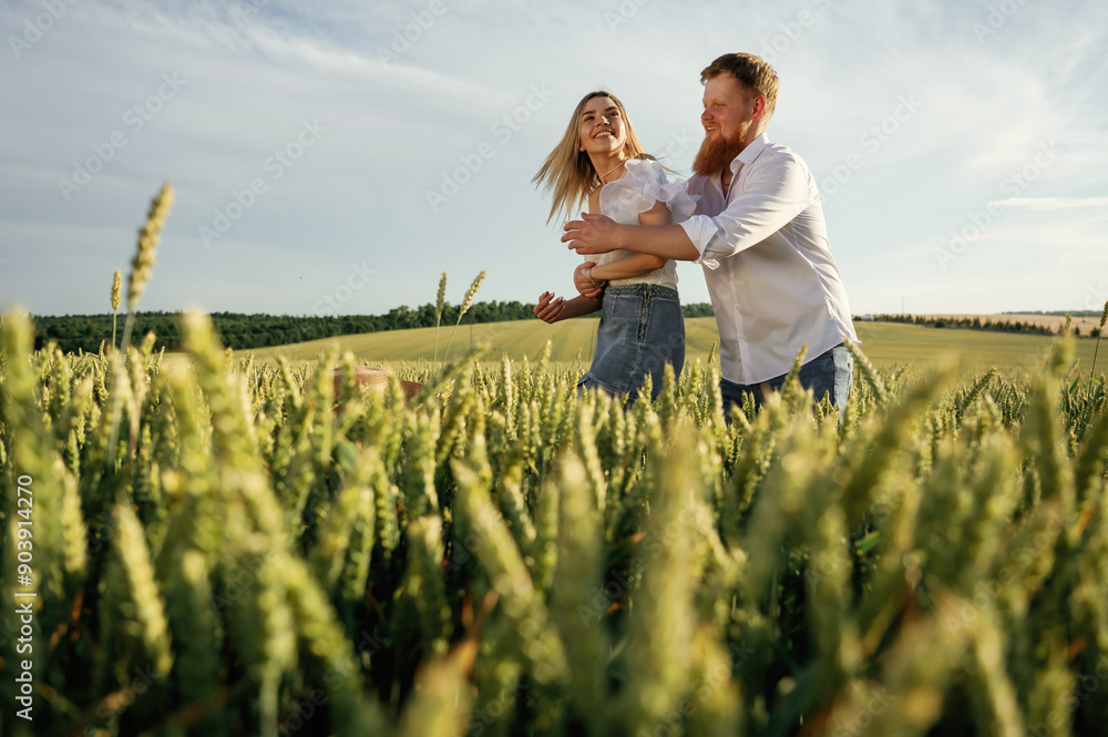 Summertime wellness, happiness. Lovely couple are on the green agricultural field together Summertime wellness, happiness. Lovely couple are on the green agricultural field together
