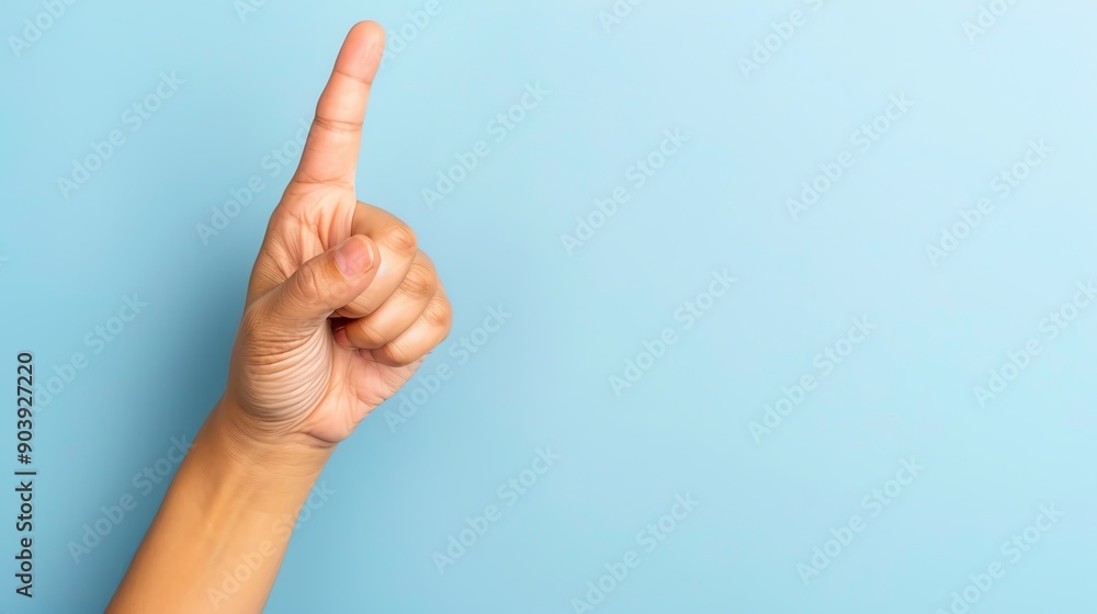 A hand raised with a finger pointing upwards against a soft blue background, symbolizing a sign of correction or emphasis. A hand raised with a finger pointing upwards against a soft blue background, symbolizing a sign of correction or emphasis.