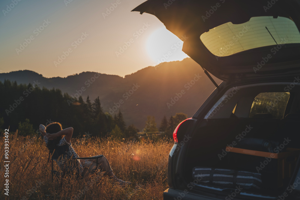Young beautiful woman traveler enjoying the sunset in the mountains while traveling