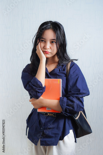 Sad and disappointed young Asian woman student holding book. concept photo back to school or campus