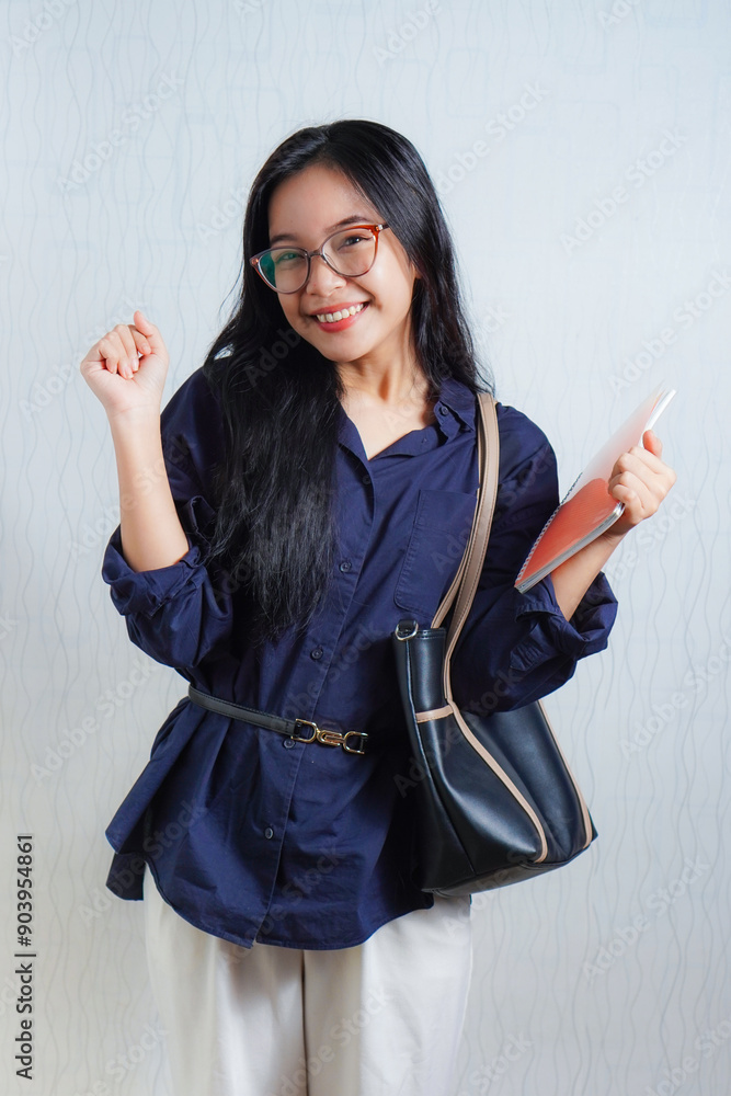 Happy young Asian woman student holding book wearing glasses look to camera. concept photo back to school or campus Happy young Asian woman student holding book wearing glasses look to camera. concept photo back to school or campus