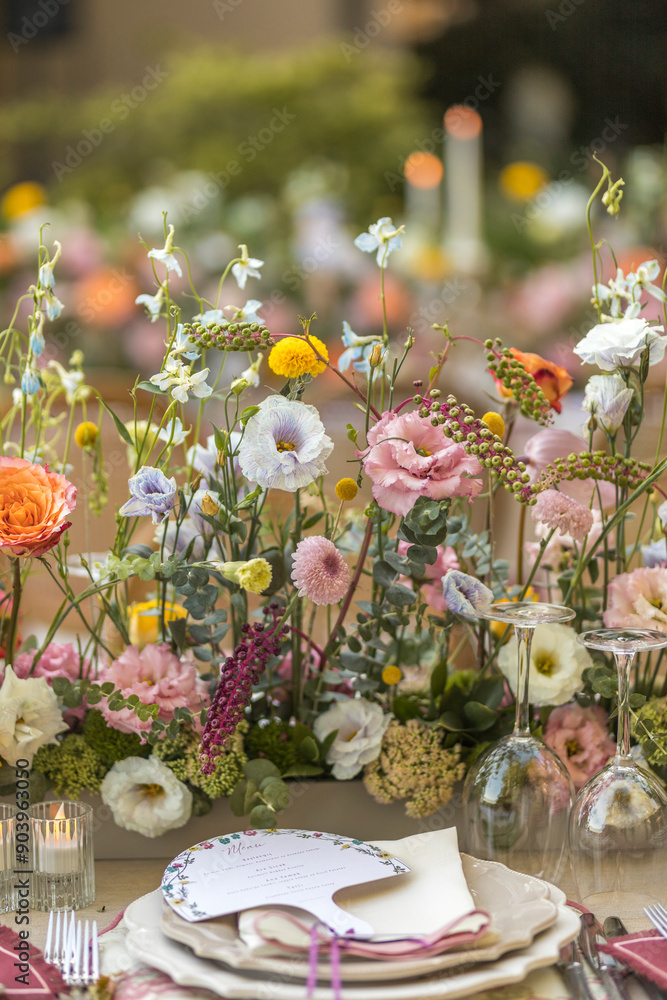Vibrant outdoor wedding table setting with colorful floral arrangements