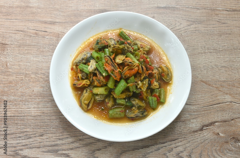 spicy stir fried mussel with slice yard long bean and basil leaf on plate 