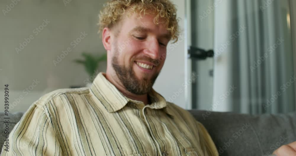 A man enters credit card details into a mobile phone for online purchases while sitting on the couch at home. A man enters credit card details into a mobile phone for online purchases while sitting on the couch at home.