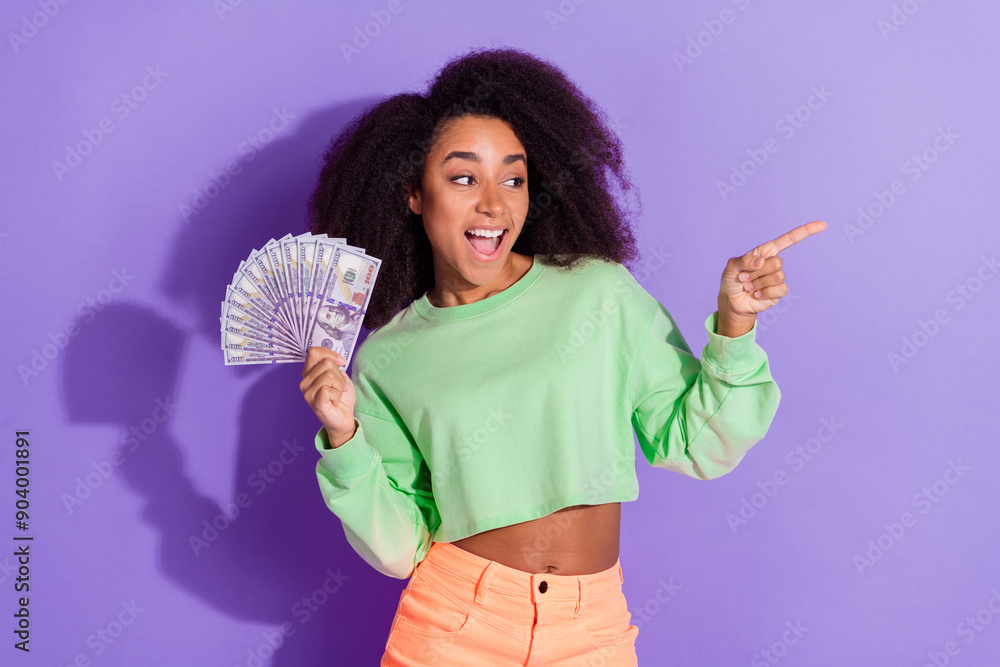 Photo of rich young girl with funny chevelure curly hair pointing finger empty space save your money isolated on purple color background Photo of rich young girl with funny chevelure curly hair pointing finger empty space save your money isolated on purple color background