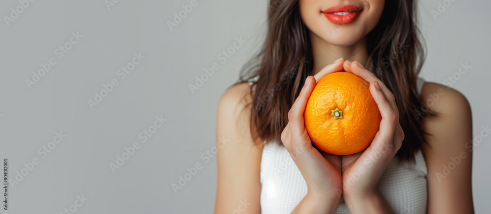 Woman holding orange as concept of nutrition diet with copy space on gray background Woman holding orange as concept of nutrition diet with copy space on gray background