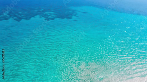 Aerial view of crystal clear ocean water with gentle waves and sandy bottom, creating a serene and tranquil seascape. 